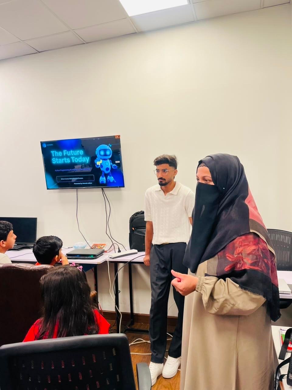 The bootcamp team addressing children beside a Python orientation presentation